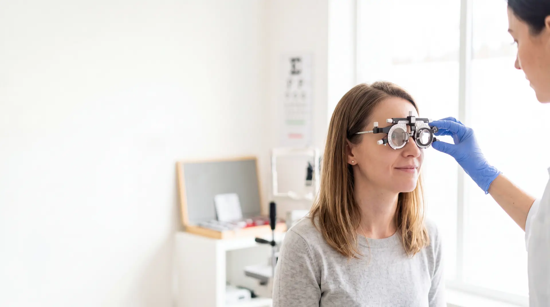 Optometrystka zakłada pacjentce oprawę próbną podczas badania wzroku